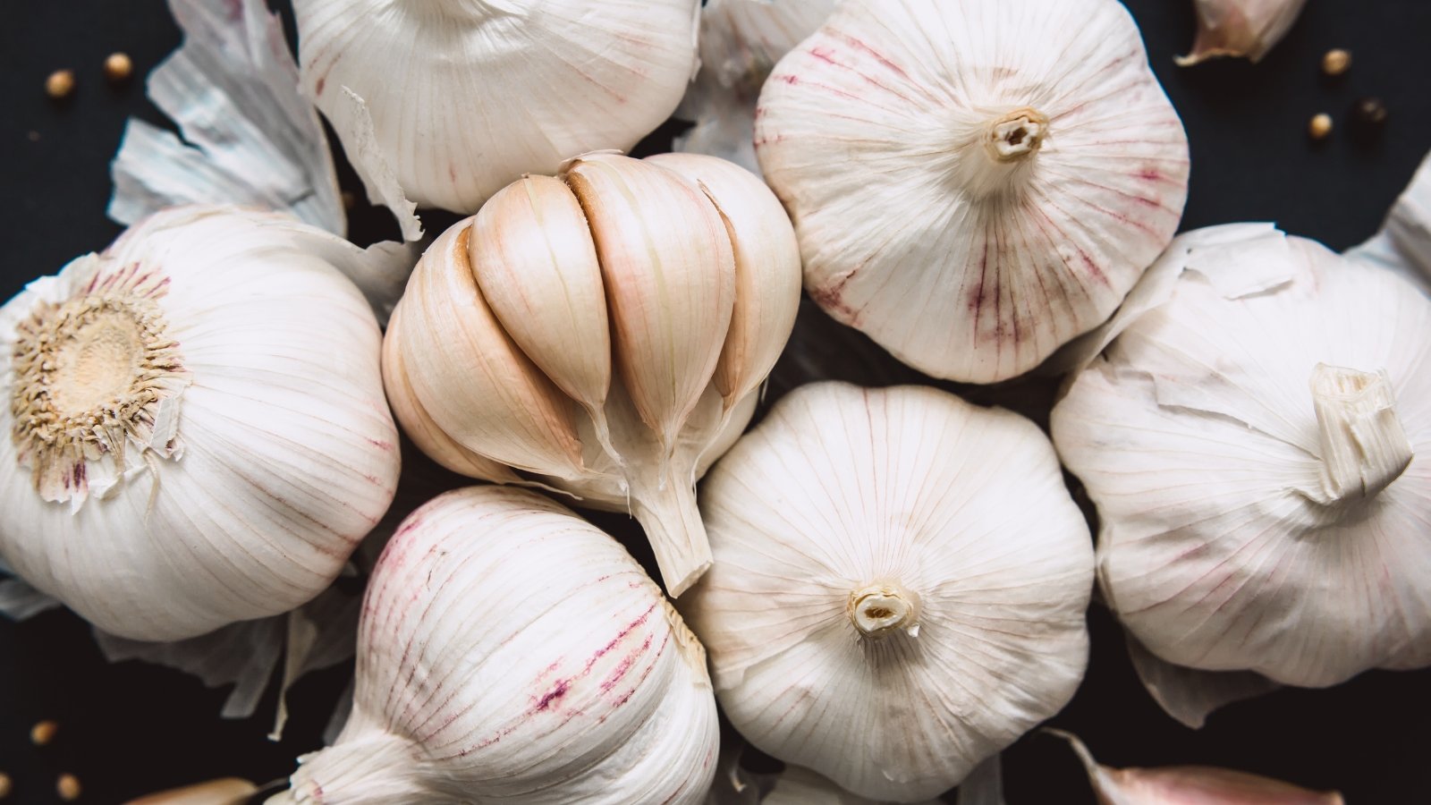 This image features several clusters of white bulbs with papery skins and smooth, rounded surfaces illuminated against a dark background, creating a striking contrast that highlights their texture and form.