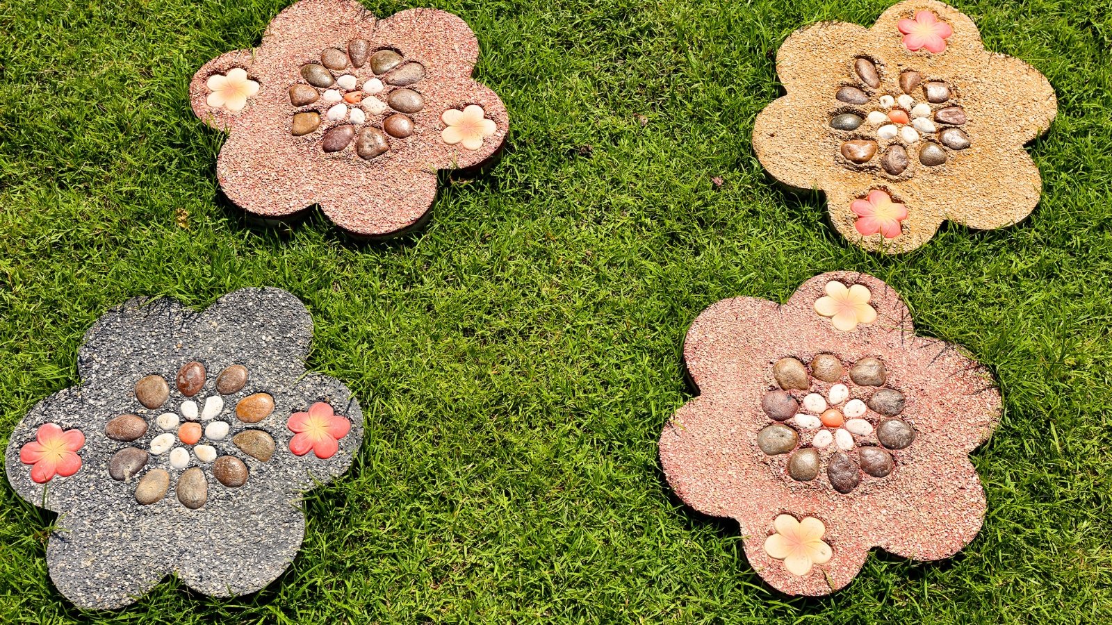 Close-up of four stepping stones shaped like flowers, with decorative stones forming the centers.
